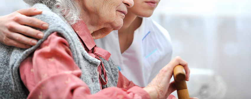 Personal care aide helping a client walk at home